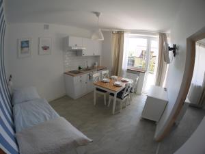 a kitchen and dining room with a table and a couch at Bajkowy Las in Pobierowo