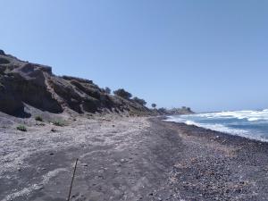 a beach with a rocky shore and the ocean at En Plo Boutique Suites in Oia