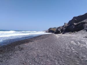 a beach with rocks and the ocean on a sunny day at En Plo Boutique Suites in Oia