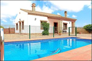 a house with a swimming pool in front of a house at Chalet Puente de Tabla in Conil de la Frontera