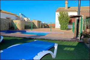 a blue bench in front of a house with a pool at Chalet Puente de Tabla in Conil de la Frontera