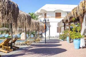 a resort with benches and straw umbrellas on a sidewalk at Aquarius Beach Hotel in Faliraki