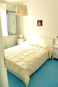 a white bed in a bedroom with a blue floor at VillaColì Menfi in Menfi