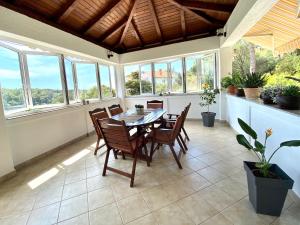 a dining room with a table and chairs and windows at Guesthouse Kurelic Rab in Kampor