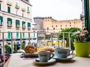 a table with two cups of coffee and pastries on a balcony at San Marco Hotel in Naples