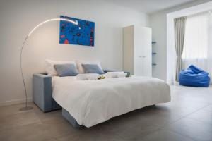 a white bedroom with a large bed and a lamp at LA ROCCA SUITE in Garda