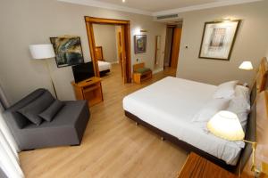 サンティアゴ・デ・コンポステーラにあるOca Puerta del Camino Hotelのベッドルーム1室(ベッド1台、椅子1脚付)