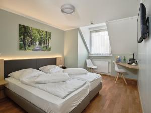 a bedroom with a bed and a desk and a window at Hotel Restaurant Clemens-August in Ascheberg