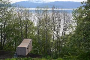 una caja de madera sentada junto a un cuerpo de agua en Treehut, nature, birds, silence and fjord, en Samlanes