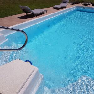 a blue swimming pool with two chairs at Garni Villa Tyrol - Adults Only in Merano