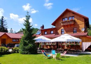 a house with chairs and tables in front of it at Zajazd PTTK Pod Roztoką in Rytro