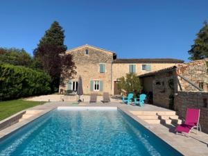 a pool in front of a house with chairs and a building at Gîte la Mirmandelle in Mirmande