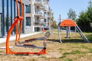 a playground with an orange swing set in a park at Apartament Słoneczny 5 Mórz in Sianozety
