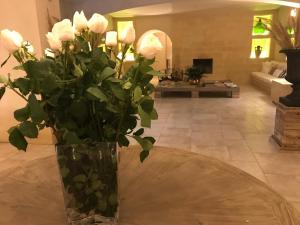 un jarrón con rosas blancas sobre una mesa en la sala de estar en Colle San Mauro, en Caltagirone