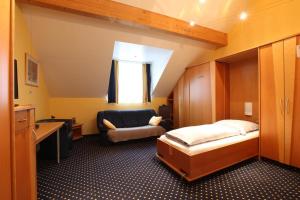 1 dormitorio con cama, silla y escritorio en Au P'tit Max - Studios hotel, en Luxemburgo