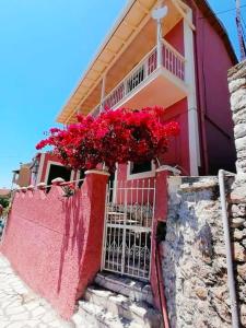 a pink house with red flowers on a fence at Traditional Panoramic Sea View House in Lákones