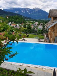a large blue swimming pool with mountains in the background at Planika Holiday Home in Bled