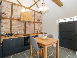 eine Küche mit einem Holztisch und einer Ziegelwand in der Unterkunft The Stables in Hereford