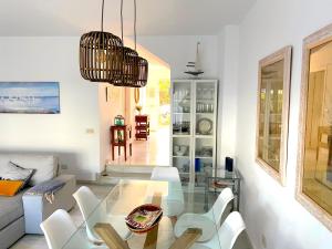 een woonkamer met een glazen tafel en witte stoelen bij PLAYA PALOMA Beach House 8PAX in Estepona
