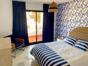 een slaapkamer met een bed met blauwe gordijnen en een raam bij PLAYA PALOMA Beach House 8PAX in Estepona