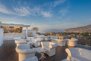 a bar with white chairs and a view of mountains at Majestic Palace Hotel in Sant'Agnello