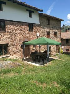 einem Tisch mit einem grünen Regenschirm vor einem Gebäude in der Unterkunft Casa Soleta Ezcaray in Ezcaray