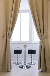deux tabourets devant une fenêtre avec rideaux dans l'établissement Royal Rooms Luxury Suite, à Naples