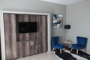 The Cato Suites Hotel في ديربان: غرفة معيشة مع تلفزيون وكرسيين زرقاء