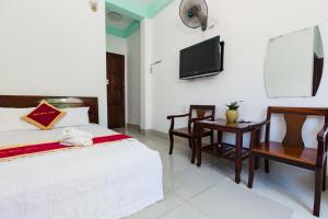 a bedroom with a bed and a tv and a table at Bách Khoa Motel in Vung Tau