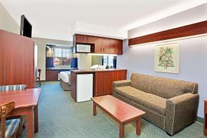 a living room with a couch and a kitchen at Microtel Inn & Suites by Wyndham Detroit Roseville in Roseville