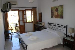 a bedroom with a white bed and a television at Michalis Studios in Leipsoi