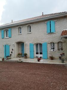 une maison avec volets bleus sur son côté dans l'établissement Chambre d’hôtes des tourterelles, à Champniers