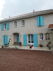 Una casa con persianas azules a un lado. en Chambre d’hôtes des tourterelles en Champniers