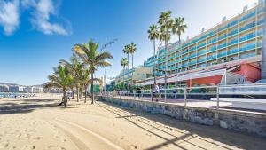 a sandy beach with palm trees and a building at Casa Canaria Beautiful Home in Las Canteras in Las Palmas de Gran Canaria