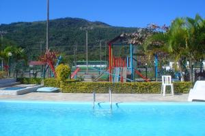 a swimming pool with a playground in the background at Praias Brancas. Boa Vida in Florianópolis