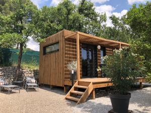 a small wooden house with a bench and a tree at La Cabane in Draguignan