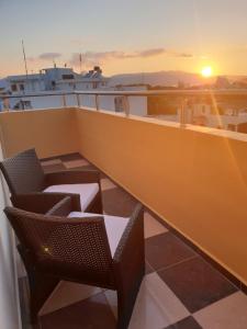 a balcony with chairs and a boat at sunset at New Gate City Break Suite in Heraklio