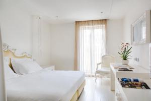 a white hotel room with a bed and a desk and a window at Boscolo Nice Hotel & Spa in Nice