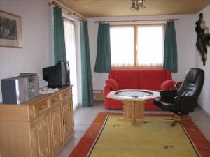 uma sala de estar com um sofá vermelho e uma televisão em Er Liung - Ferienwohnung für max. 3 Personen em Falera