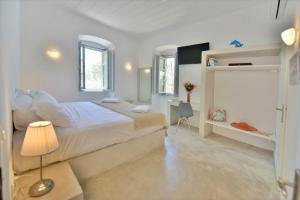 a white bedroom with a large bed and a desk at Loukia's Apartments in Hydra