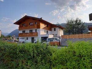 um grande edifício branco com um telhado de madeira em Die Atempause - appartements em Flachau