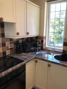 a kitchen with white cabinets and a sink and a window at Chauffeurs Cottage at The Stoep in Paignton