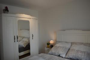 ein weißes Schlafzimmer mit einem Bett und einem Spiegel in der Unterkunft Ludwig XIV in Saarlouis