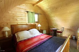 1 dormitorio con 1 cama en una cabaña de madera en Domaine de La Couture, en Évaux-les-Bains