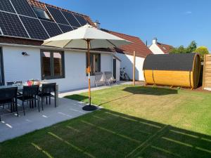 a patio with a table and an umbrella in a yard at Duinendaele 166 in De Panne