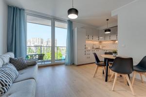 uma sala de estar com um sofá e uma mesa com cadeiras em Wave Apartments - SOLVO em Gdansk