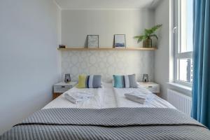 um quarto com uma cama com duas almofadas e uma janela em Wave Apartments - SOLVO em Gdansk