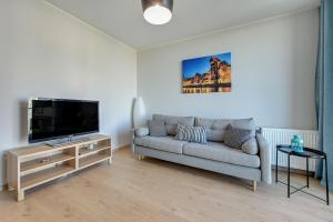 a living room with a couch and a flat screen tv at Wave Apartments - SOLVO in Gdańsk