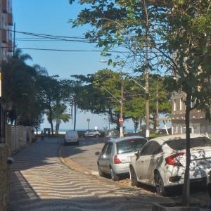 une rue avec des voitures garées sur le côté de la route dans l'établissement Flat Gonzaga Praia, à Santos