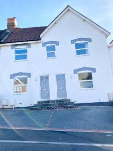 a white house with blue doors and stairs at Modern New House - Great Location - Garden - Parking - Fast WiFi - Smart TV - Stunning 2 Bedroom House sleeps up to 4! Only 5 mins drive to Sandbanks Beach in Parkstone
